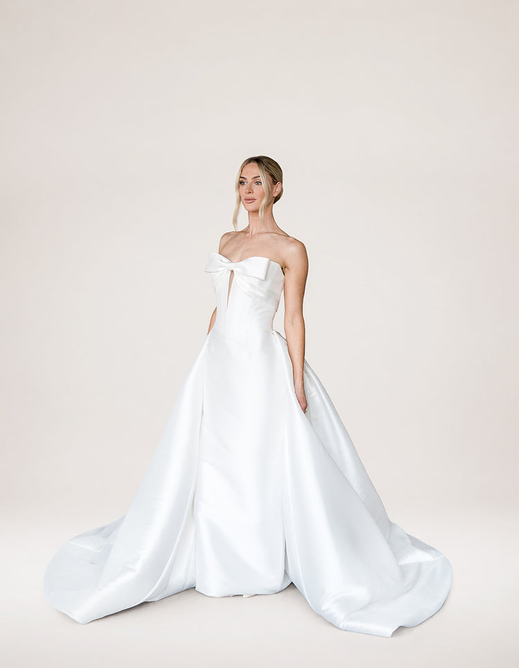 Amira with Keyhole by Aura by Archela - strapless satin sheath with bow detail, keyhole plunge, boned bodice and overskirt with train